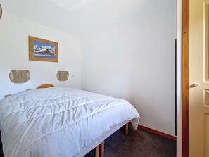 A bedroom with a bed, a wall-mounted picture, and a door. - 3-room apartment, southwest balcony, at the foot of slopes (Les Menuires)