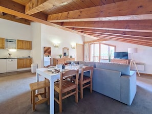 A cozy living area with a dining table, chairs, a sofa, and a television. - 3-room apartment, southwest balcony, at the foot of slopes (Les Menuires)