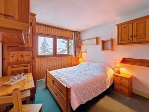 A wooden cabin-style bedroom with a bed, bedside tables, a desk, and a window with a view of trees. - Spacious apartment - 6 guests at the foot of the slopes (Les Menuires)