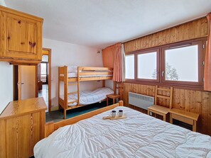 A bunk bed room with wooden walls, a window with curtains, a radiator, and a bedside table with two cups. - Spacious apartment - 6 guests at the foot of the slopes (Les Menuires)