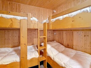 Ein Schlafzimmer mit Etagenbetten, Holzwänden und einer Leiter.