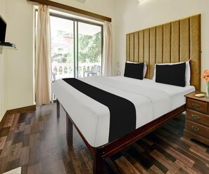 Habitación de hotel con una cama grande, cabecera de madera y vistas al balcón exterior a través de una puerta corredera.