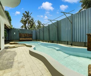 Una piscina con borde curvo, rodeada por un muro bajo y una zona pavimentada.