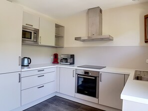 A compact kitchen with white cabinets, a microwave, a coffee maker, and a Bosch oven. - Spacious 7-room apartment near slopes with sauna, hammam, and wifi (Les Menuires)