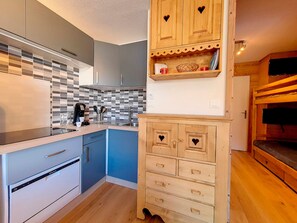 Eine kompakte Küche mit modernen Geräten, einer gefliesten Spritzschutzwand und Holzschränken.