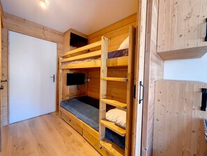 Ein Zimmer mit einem Etagenbett, einem an der Wand befestigten Fernseher und Holzmöbeln.