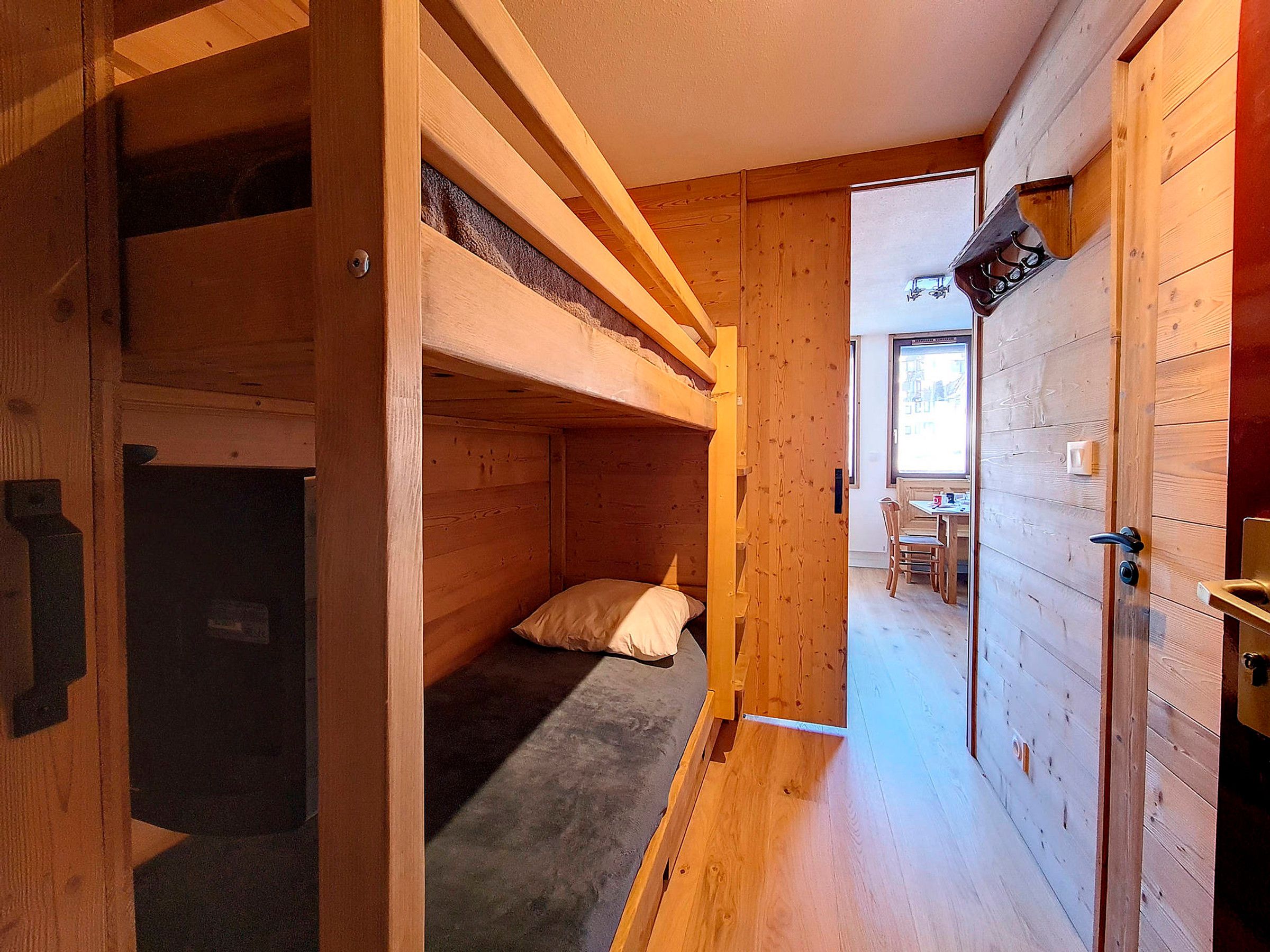 Un intérieur en bois avec des lits superposés, un coin repas et une porte dotée d’un porte-serviettes.