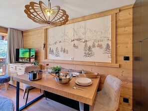 A modern kitchen with a wooden table, chairs, and a large decorative wall. - Renovated apartment with balcony, ski-in/ski-out, 4 people (Les Menuires)