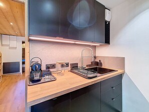 A modern kitchen with a wooden countertop, a built-in sink, and a coffee machine. - Renovated apartment with balcony, ski-in/ski-out, 4 people (Les Menuires)