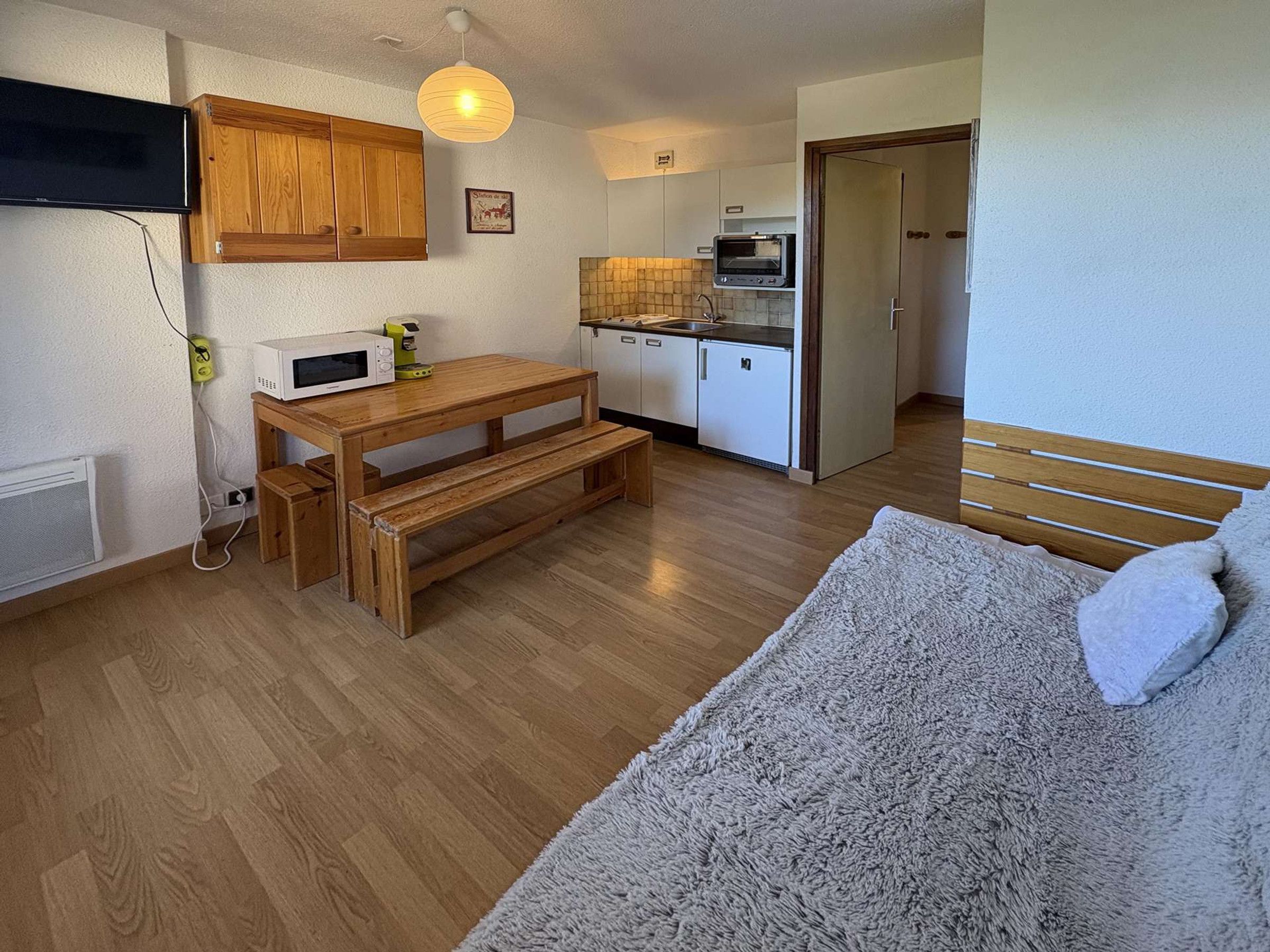 A compact kitchen with a microwave, toaster oven, and wooden cabinets.