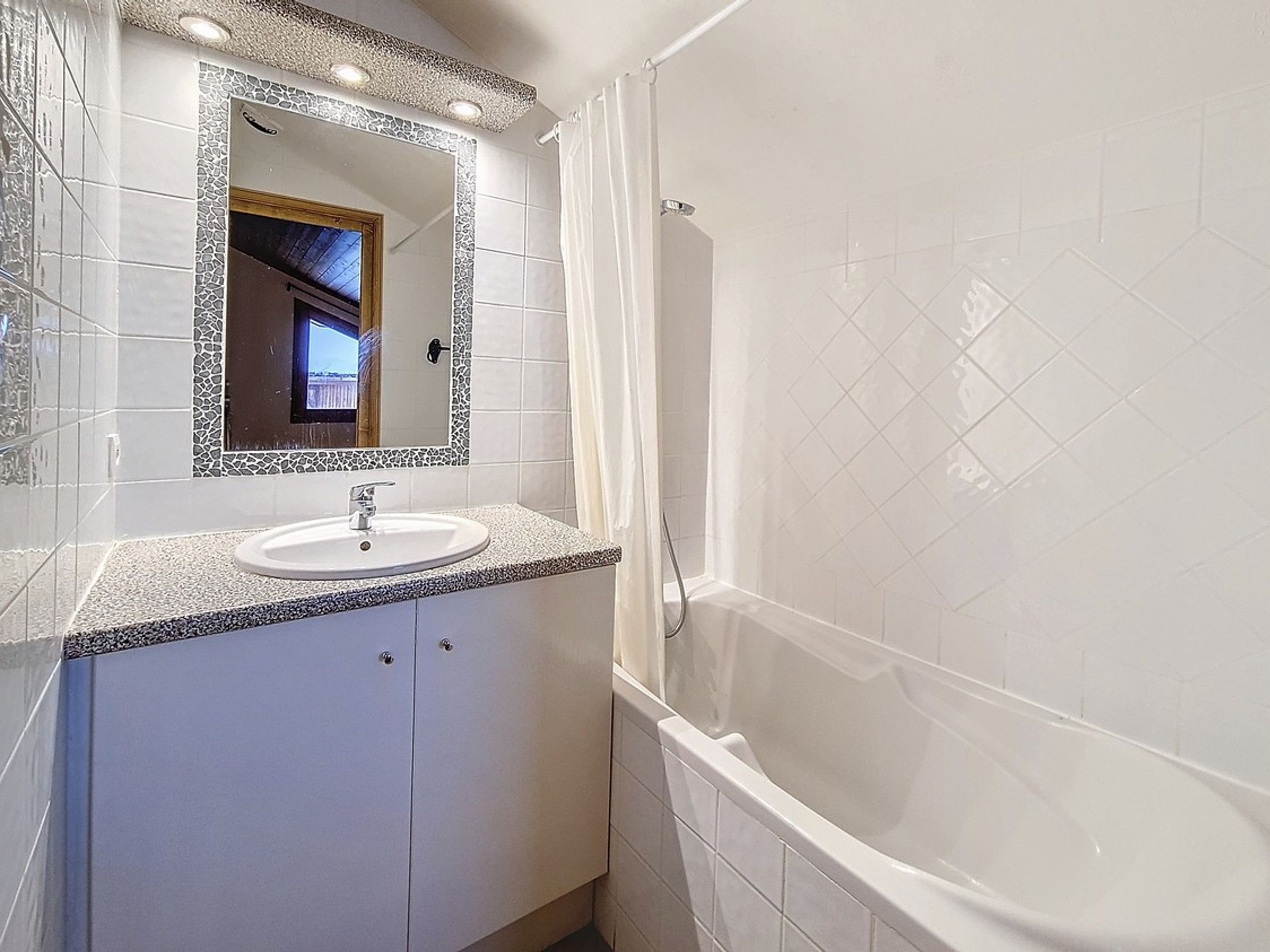 Een badkamer met een wastafel, spiegel en bad.