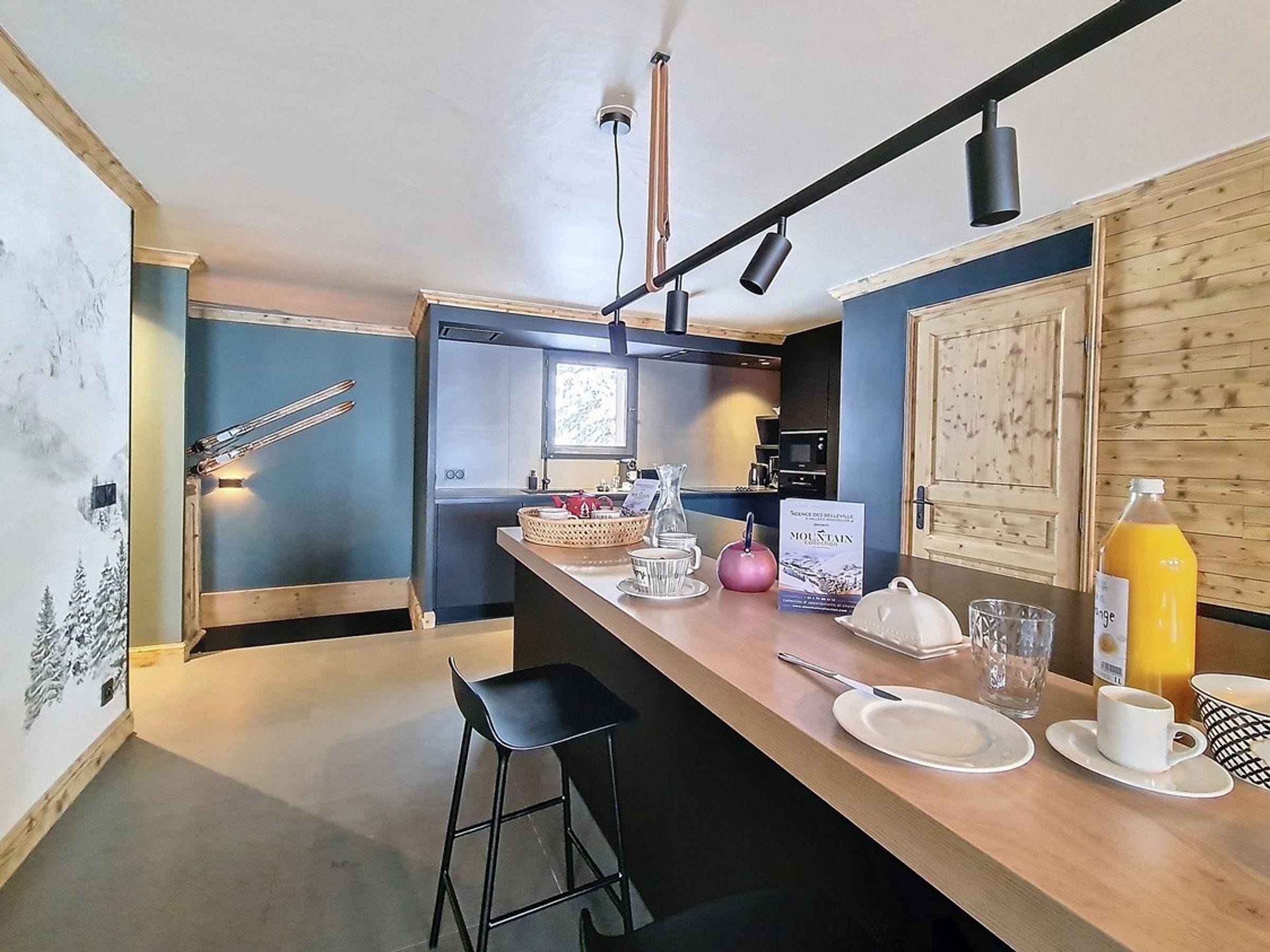 A modern kitchen with a wooden island, bar stools, and a view of the living area.