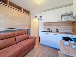 A compact living space with a sofa, kitchenette, and a microwave. - Renovated studio at the slopes with WIFI (Les Menuires)