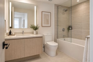 Une salle de bain moderne avec une douche à parois de verre, des toilettes et un meuble-lavabo avec un miroir.