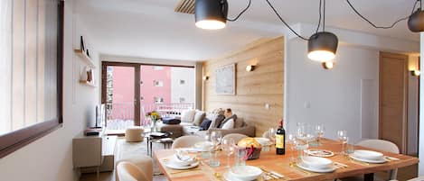 A dining area with a wooden table set for a meal, a sofa, and a view of a building outside.