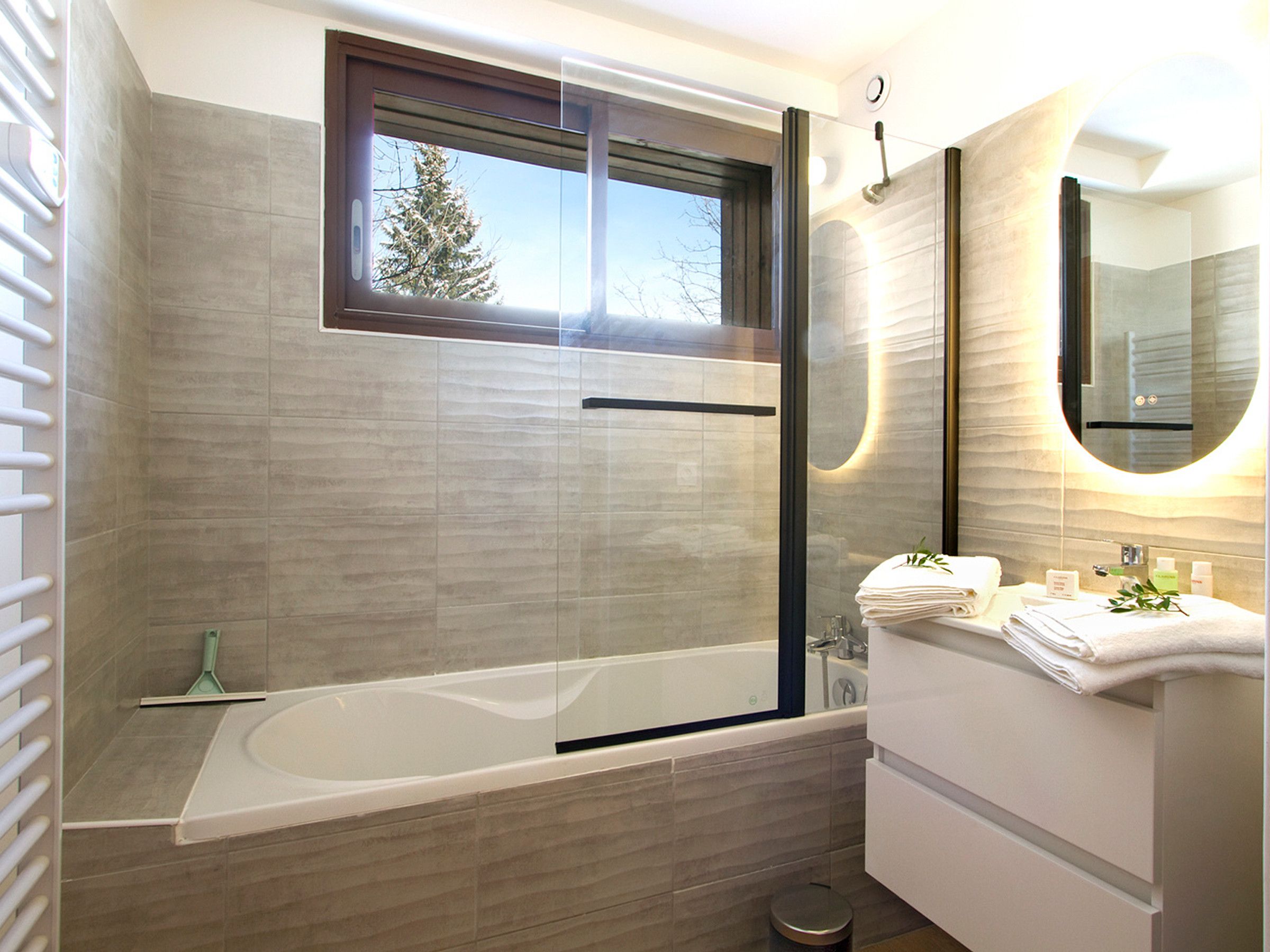 A modern bathroom with a glass-enclosed shower, a bathtub, and a vanity with a mirror.