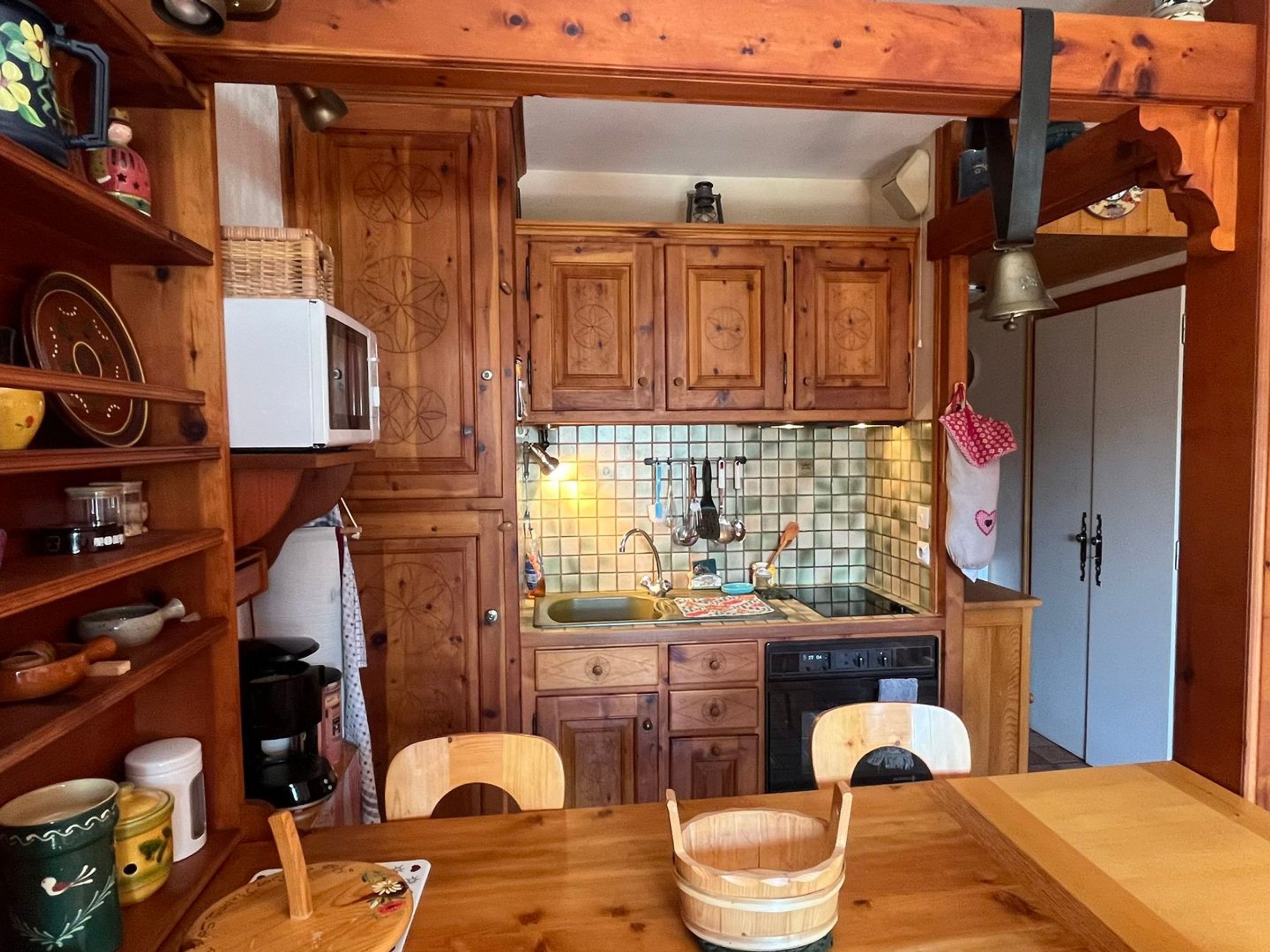 A kitchen with wooden cabinets, a microwave, a sink, and a wooden table with a bowl.
