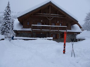 Een houten chalet met een balkon, omringd door met sneeuw bedekte bomen.