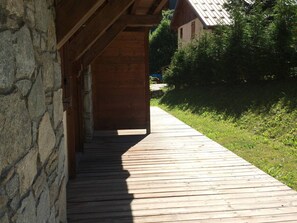 A wooden pathway leading to a building with a stone wall on one side. - 3-room apartment South facing - 4 guests (Valloire)
