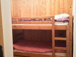 Een stapelbed met een houten hoofdbord en een onderste bed met een roze matras.