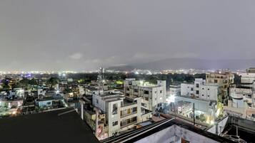 A cityscape at night with buildings and a distant mountain range.