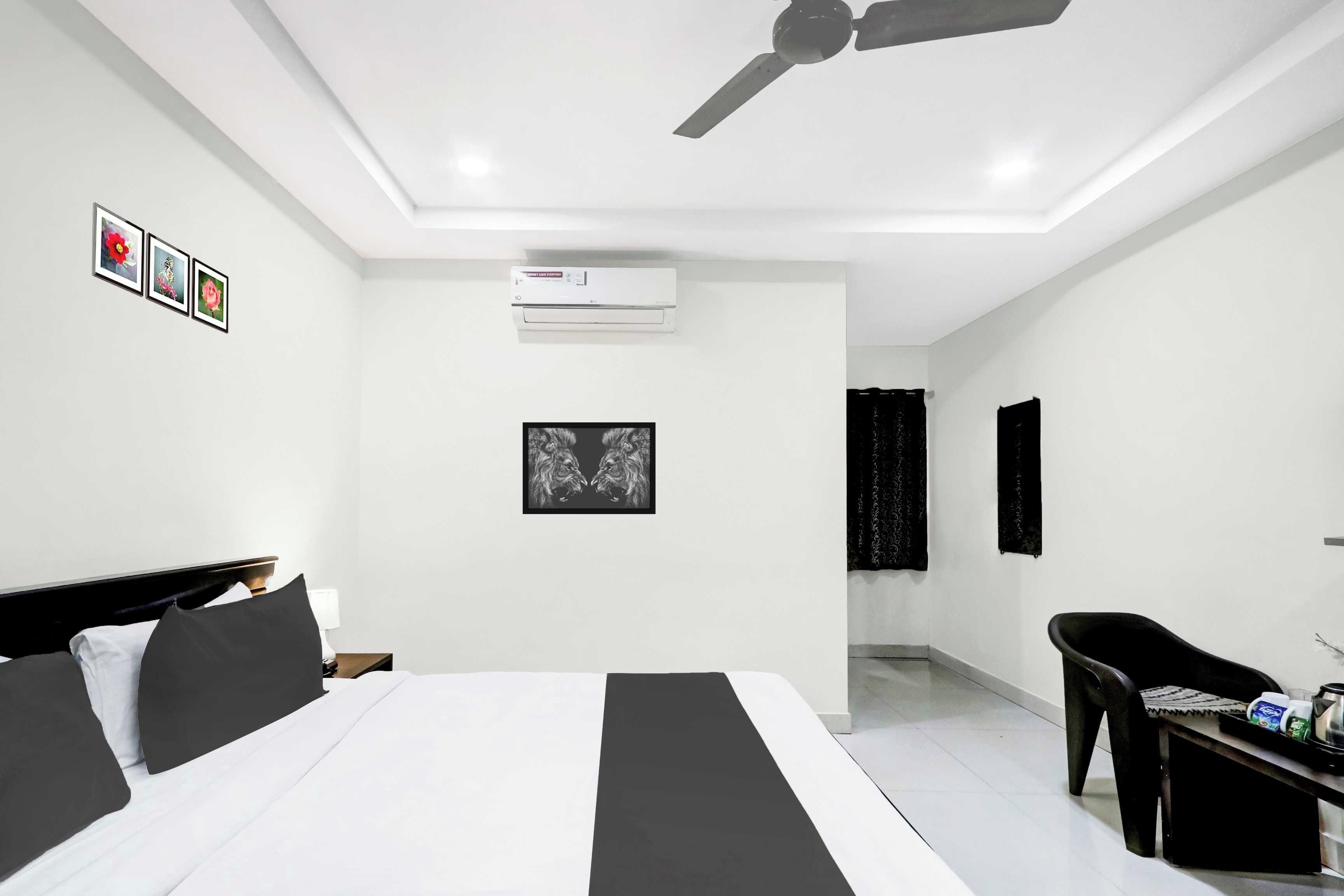 A modern hotel room with a bed, a desk, a chair, an air conditioning unit, and a ceiling fan.