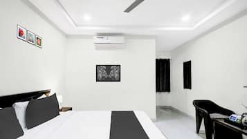 A modern hotel room with a bed, a desk, a chair, an air conditioning unit, and a ceiling fan.