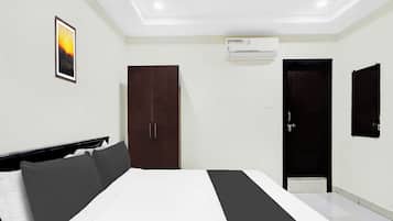 A bedroom with a bed, a wardrobe, a door, and an air conditioning unit.