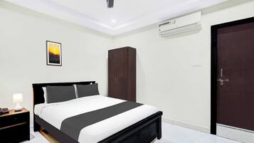 A modern bedroom with a bed, bedside table, lamp, wardrobe, and an air conditioning unit.