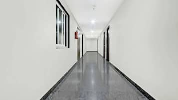 Un pasillo largo y estrecho con paredes blancas y piso pulido.