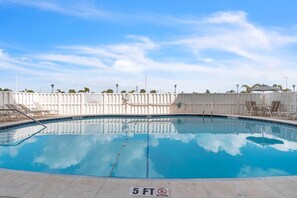 A clear swimming pool with a 5 ft depth marker, surrounded by a white fence and lounge chairs. - Beachfront Condo | Heated Pool | Private Balcony - Gulf Shores #404 (Indian Shores)