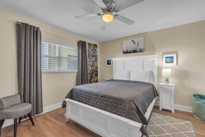 A bedroom with a bed, a chair, a nightstand, a lamp, and a ceiling fan. - Beachfront Condo | Heated Pool | Private Balcony - Gulf Shores #404 (Indian Shores)