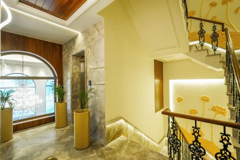 A modern interior with a marble floor, a wooden ceiling, a staircase with black railings, and potted plants.