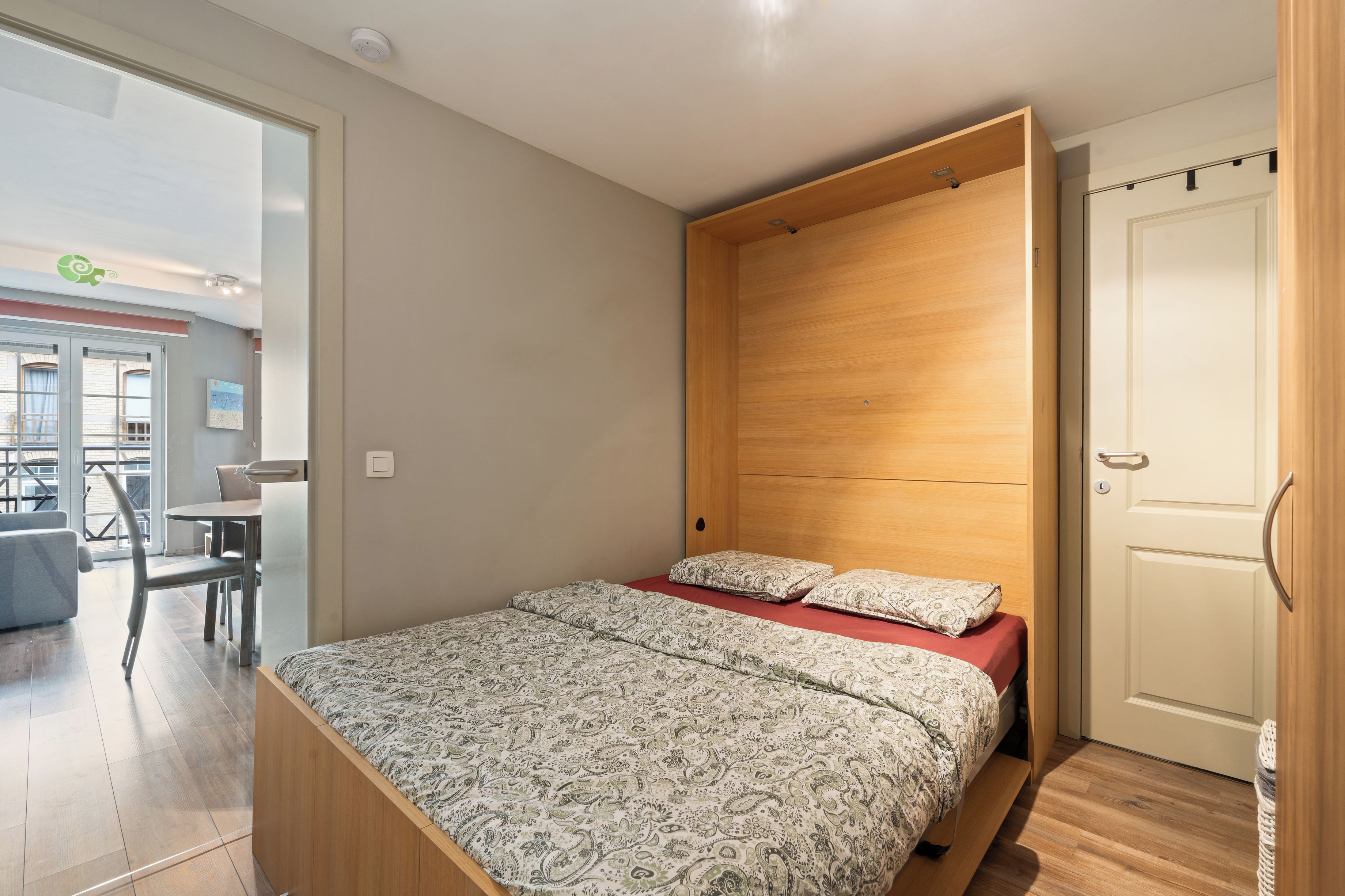 Ein Schlafzimmer mit einem Bett, einem Holz-Kopfteil, einem Schreibtisch und einem Stuhl.