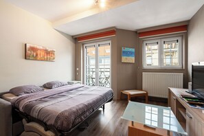 A bedroom with a bed, a desk, a chair, and two windows. - 1 bedroom accommodation in Middelkerke (Middelkerke)