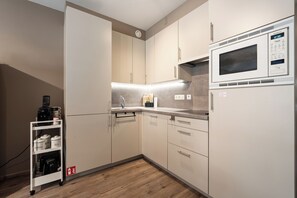 Eine moderne Küche mit integriertem Mikrowellenherd, einer Kaffeemaschine und einem Regal mit Kaffe- und Teebehältern.