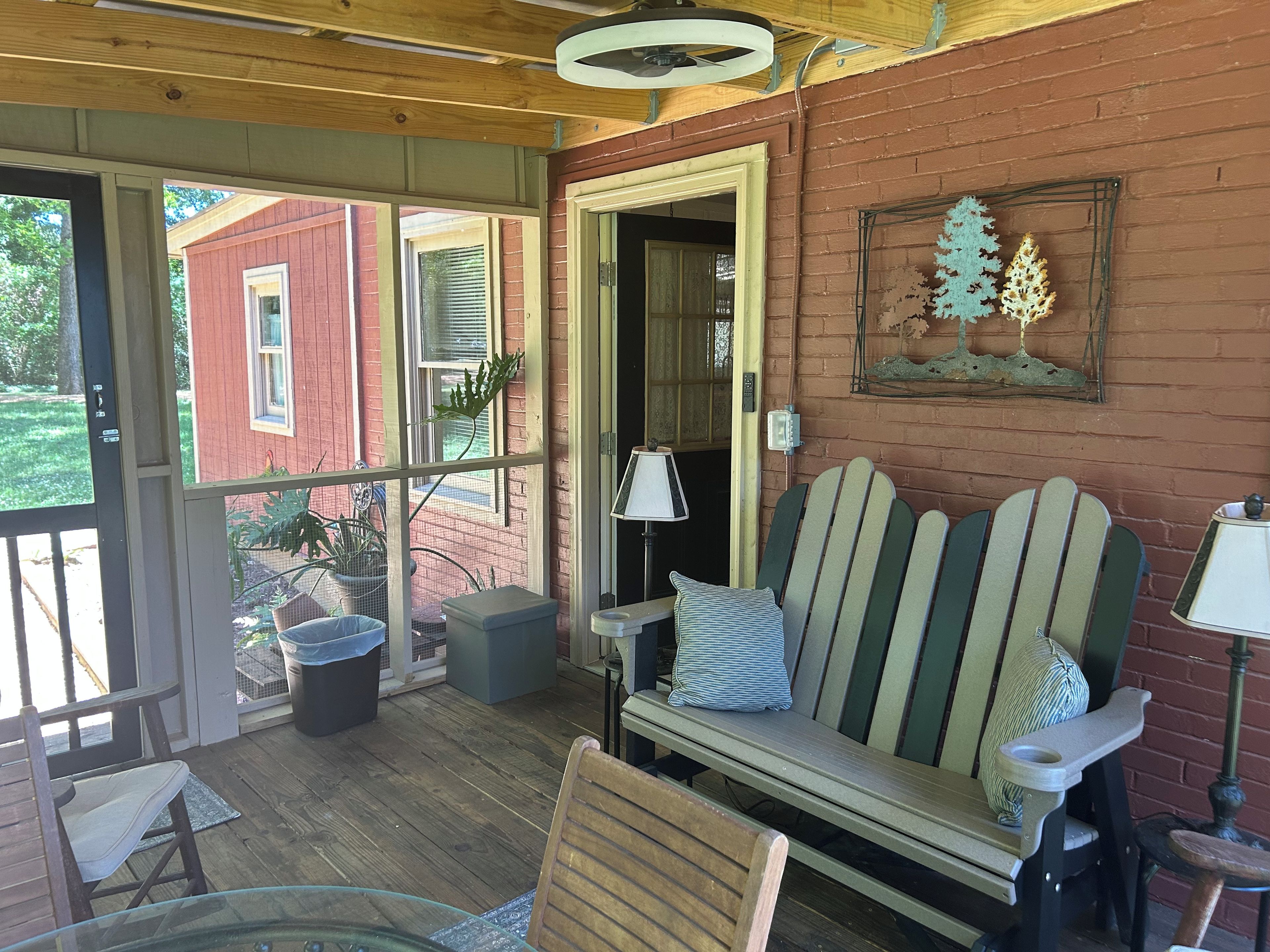 Une véranda abritée avec un banc en bois, une table et des chaises.