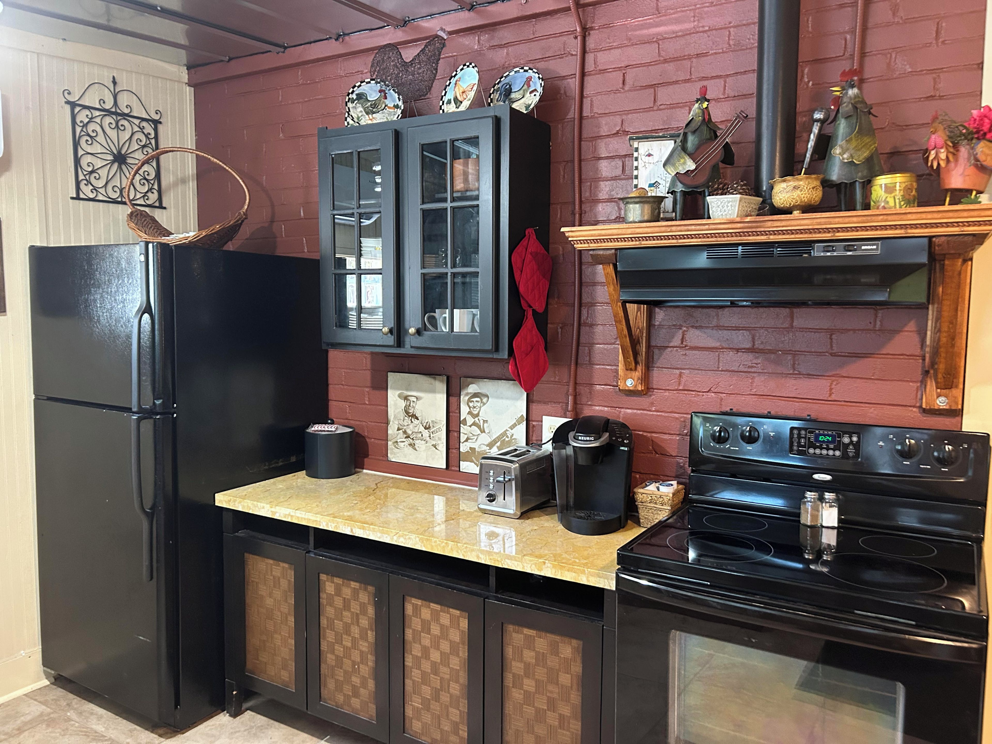 A kitchen with a black refrigerator, a coffee maker, a toaster, and a stove.
