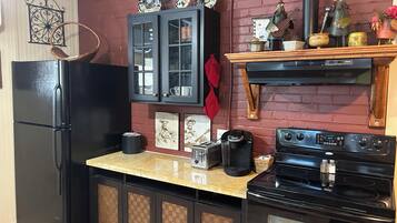A kitchen with a black refrigerator, a coffee maker, a toaster, and a stove.