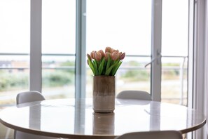 A round table with a vase of flowers in the center, placed on a balcony with a view of the outdoors. - 2 bedroom accommodation in Middelkerke (Middelkerke)