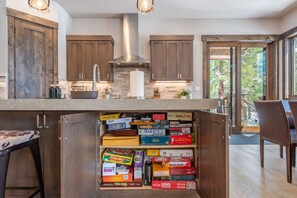 Une cuisine dotée de meubles en bois, d’une hotte en acier inoxydable et d’un plan de travail sur lequel sont disposés divers jeux de société.
