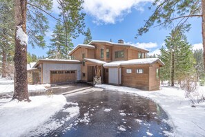 Une cabane en bois avec un garage, une allée couverte et un paysage enneigé.
