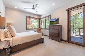 Ein Schlafzimmer mit Bett, Schminktisch, Fernseher und großen Fenstern.