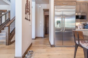 Eine moderne Küche mit Edelstahlgeräten, einer Holztreppe und einem Essbereich mit einem Stuhl.