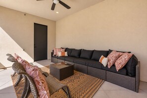 A modern living room with a dark sofa, a glass coffee table, and woven floor mats. - On The Rocks Shaken 6 Bedroom Home (Hurricane)
