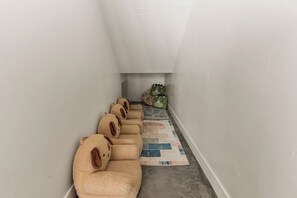A narrow hallway with a row of beige, plush, animal-shaped cushions aligned against the wall, a patterned rug on the floor, and a small seating area with a green cushion and a patterned pillow. - On The Rocks Shaken 6 Bedroom Home (Hurricane)