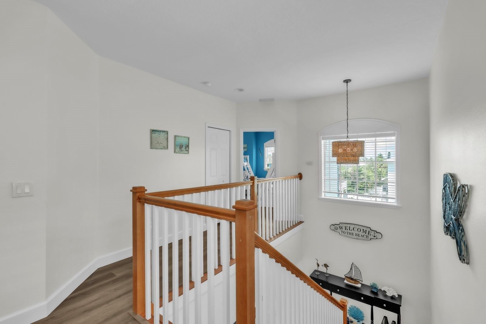 A staircase with wooden railings leading to a landing with a view of the outdoors.