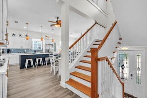 A modern kitchen with white cabinets, a central island, and bar stools. - Blue Star Oasis 4 Bedroom Home (Holmes Beach)