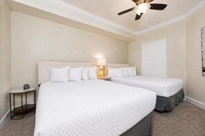 Ein Hotelzimmer mit zwei Betten, einem Deckenventilator, einem Nachttisch mit Lampe und einer Tür.