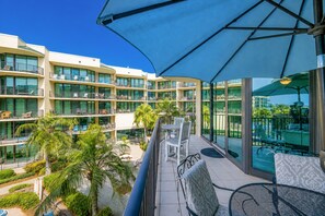 A hotel balcony with outdoor seating, a pool, and a view of the building's multiple floors. - Phoenix On The Bay 1323 2 Bedroom Condo (Orange Beach)